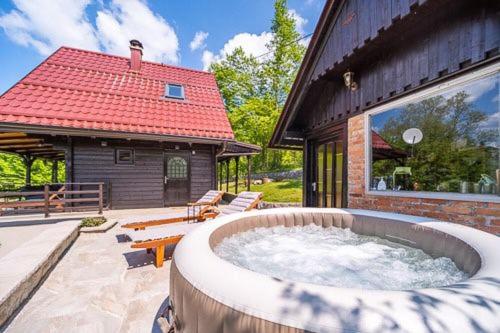 un patio con bañera de hidromasaje frente a un edificio en Kuća za odmor Šum slapa, en Karlovac