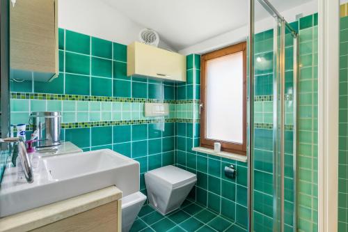 Baño de azulejos verdes con lavabo y aseo en Appartamento Monteleone en Carbonia