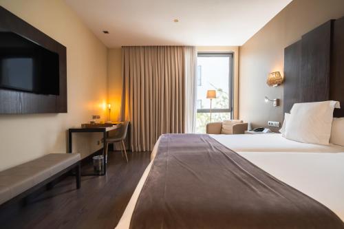 a hotel room with a bed and a desk and a television at La Laguna Gran Hotel in La Laguna
