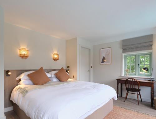 a bedroom with a large white bed and a desk at Castle Hill Cottage in Crowborough