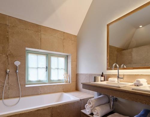 ein Badezimmer mit einer Badewanne, einem Waschbecken und einem Spiegel in der Unterkunft Castle Hill Cottage in Crowborough