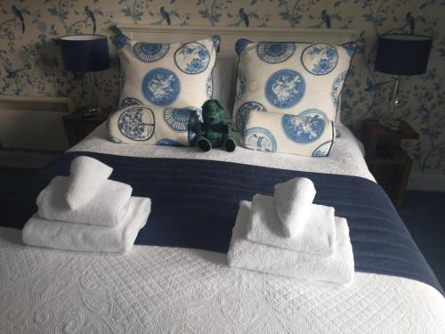 Una cama con toallas y una rana rellena sentada en ella. en Smiddy House, en Spean Bridge