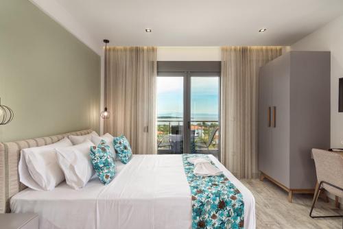 a bedroom with a large white bed with blue pillows at THEA Luxury Apartments in Vourvourou