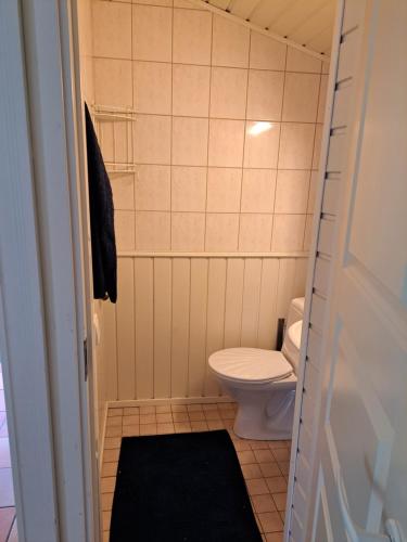 uma pequena casa de banho com um WC e um tapete preto em Norrby Gård - Sjövik em Raseborg