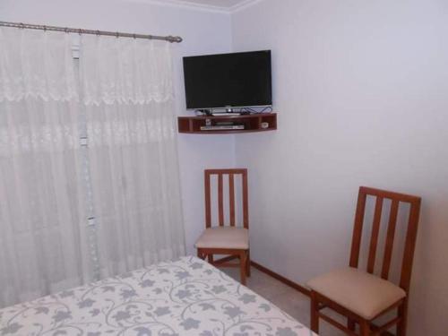 1 dormitorio con 1 cama, 2 sillas y TV en Locaciones Colon en Colón