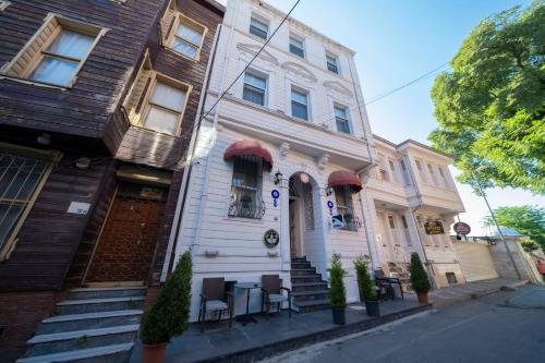 Solomon's Mansion Hotel Istanbul في إسطنبول: بيت ابيض وامامه كراسي وطاولات