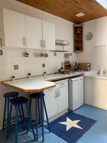 une cuisine avec des placards blancs, une table et des tabourets dans l'établissement Maison de charme en centre ville, à Duras