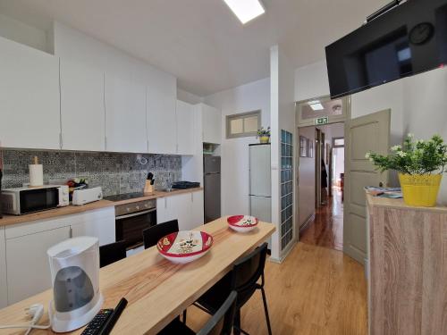 a kitchen with white cabinets and a wooden table at Casa Mosteiro in Alcobaça