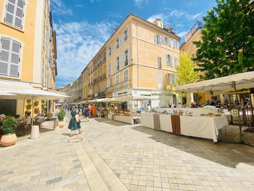 Una donna che cammina per una strada con tavoli e palazzi di CasaJoy, MS, Aix-en-Provence ad Aix en Provence