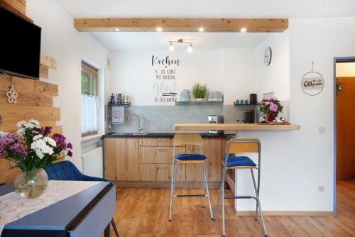 a kitchen with two bar stools and a counter at Aschaubichl - Wohnung Enzian in Grainau