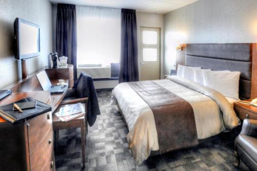 a hotel room with a bed and a desk at Hotel Continental Centre-Ville in Val-dʼOr