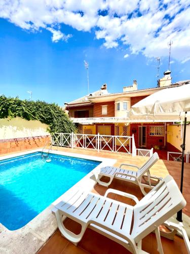 una piscina con 2 tumbonas junto a una casa en La casa de María, en Linares