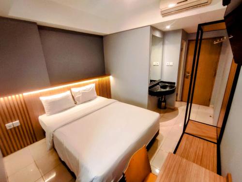 1 dormitorio con cama blanca y espejo en Studio One Thamrin Hotel, en Yakarta