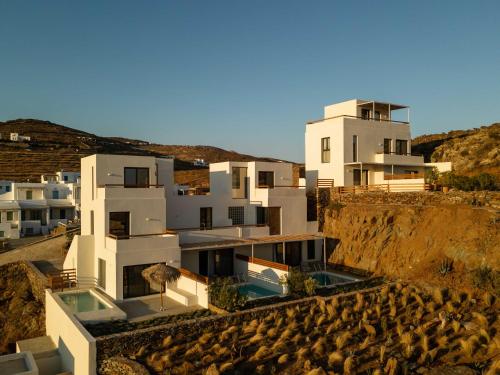 een wit huis op een heuvel met gebouwen bij Aura Villas Tinos in Agios Romanos