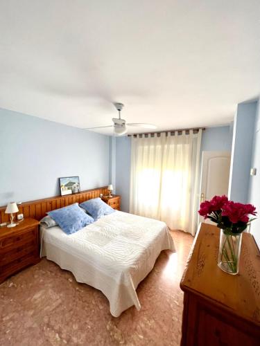 um quarto com uma cama e um vaso de flores em La casa de María em Linares