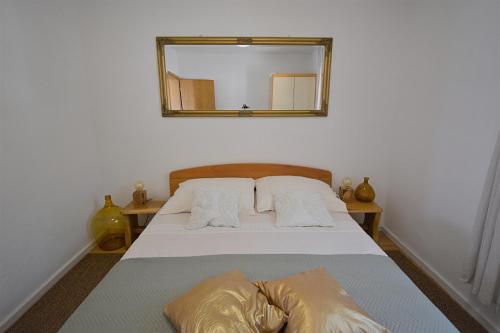 a bedroom with a bed with a mirror on the wall at Robinson House Bosiljka in Dobropoljana
