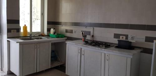 a kitchen with white cabinets and a sink and a stove at Appartement S+2 in Sousse