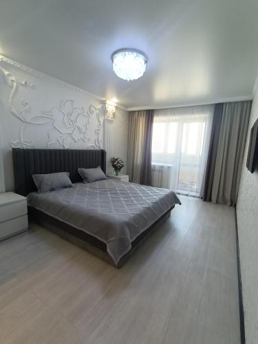 Un dormitorio con una cama grande y una lámpara de araña. en Трёхкомнатная квартира ВИП en Kokshetau