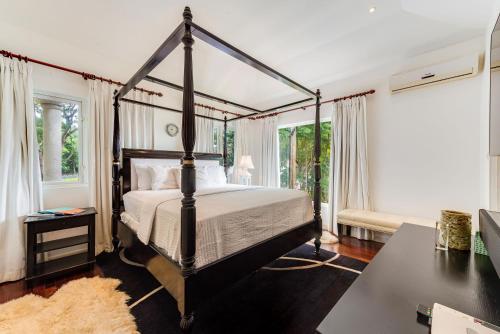 a bedroom with a four poster bed and windows at The Palms Resort in Saint James