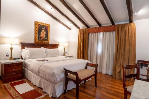 a bedroom with a large bed and a table and chairs at Hotel Boutique Santa Lucia in Cuenca