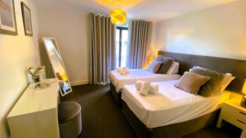 a hotel room with two beds and a mirror at 1 Rockham - Luxury Apartment at Byron Woolacombe, only 4 minute walk to Woolacombe Beach! in Woolacombe