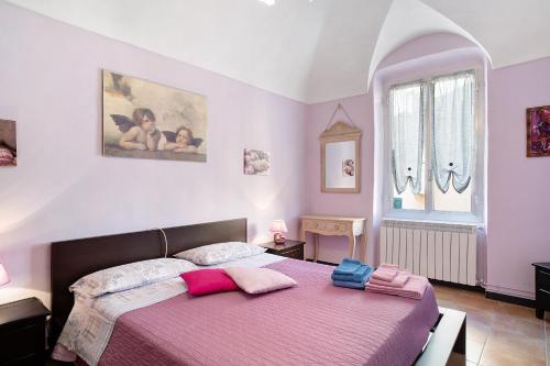 um quarto com uma cama com lençóis rosa e roxo em Casa Acqua Mare Parasio em Imperia