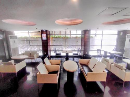 - un restaurant avec des tables et des chaises blanches dans une salle dans l'établissement Studio One Thamrin Hotel, à Jakarta