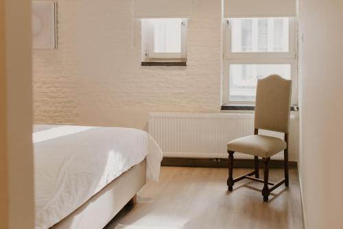 a bedroom with a bed and a chair and a window at Blue Bird Residence Wijngaard in Antwerp