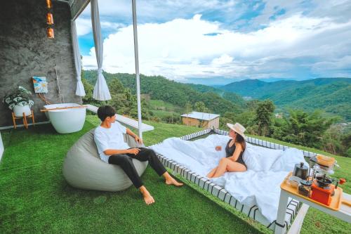 a man and a woman sitting on a bed on the grass at ไนท์สกาย โฮมสเตย์ in Ban Mae Na