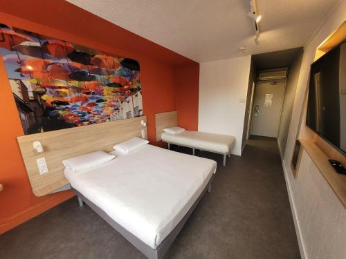 een slaapkamer met een bed en een schilderij aan de muur bij KYRIAD DIRECT LYON NORD - Dardilly in Dardilly