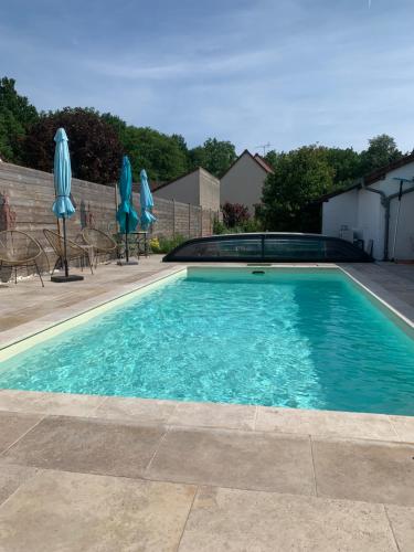 - une piscine avec des chaises et des parasols bleus dans l'établissement Les Garçonnières de Sologne, à Salbris
