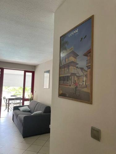 een woonkamer met een bank en een foto aan de muur bij Beau T2 tout confort in Cayenne