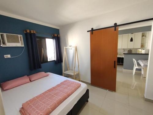 um quarto com uma cama e uma porta para uma cozinha em Pérola Home - Guarujá no Guarujá