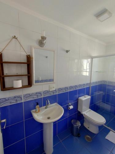 uma casa de banho azul e branca com um lavatório e um WC em Pérola Home - Guarujá no Guarujá