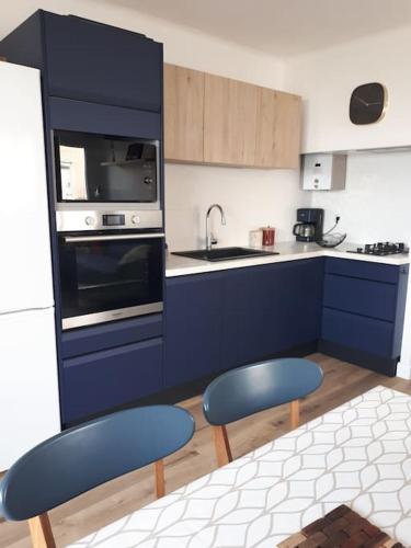 une cuisine avec des placards bleus et 2 chaises bleues dans l'établissement Direction Sud !, à Narbonne-Plage