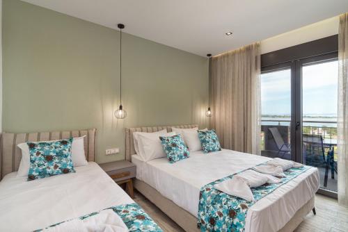 two beds in a room with a window at THEA Luxury Apartments in Vourvourou