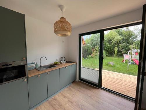 a kitchen with a sink and a large window at Liwia Park Green House in Niechorze