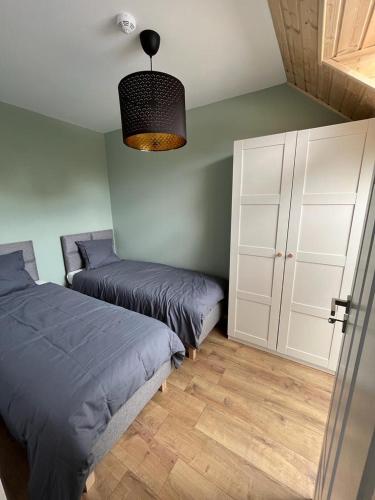 a bedroom with two beds and a chandelier at Liwia Park Green House in Niechorze