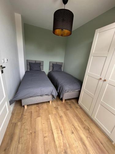 a bedroom with two beds and a door at Liwia Park Green House in Niechorze