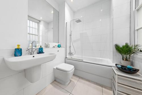 a white bathroom with a sink and a toilet and a tub at Luxurious 3-Bedroom Flat in London Sleeps 14 HY1 in London