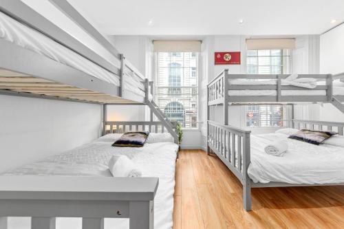 two beds in a room with two bunk beds at Luxurious 3-Bedroom Flat in London Sleeps 14 HY1 in London