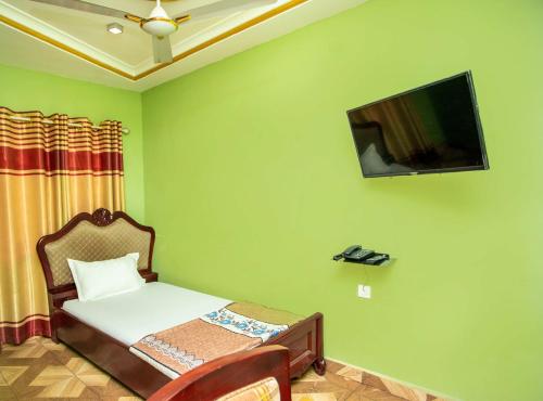 a bedroom with a bed and a tv on the wall at Glory Hills Hotel in Kumasi