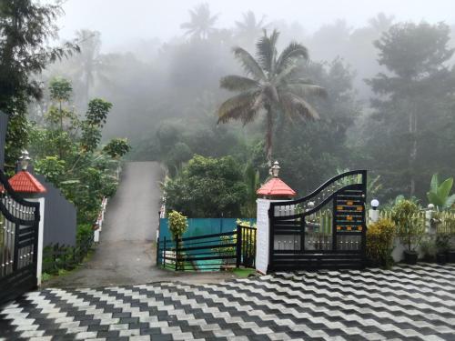 a gate on a driveway with a palm tree in the background at Arabian Nights Munnar Pool Villa in Munnar