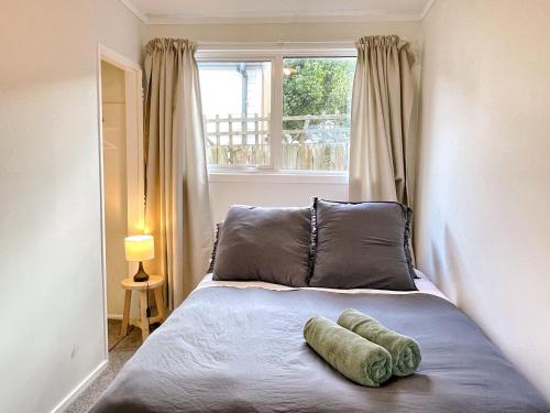 un letto con due cuscini e una finestra in una camera da letto di Cozy n Comfortable,5 mins to airport a Wellington