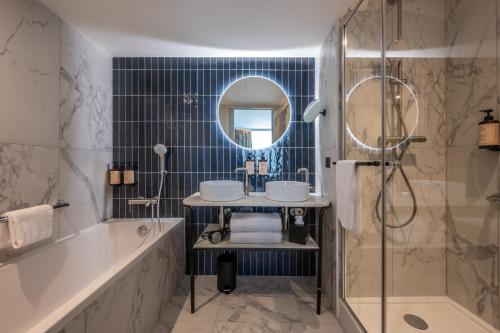 ein Badezimmer mit einer Badewanne, einem Waschbecken und einem Spiegel in der Unterkunft Mercure La Rochelle Vieux Port in La Rochelle
