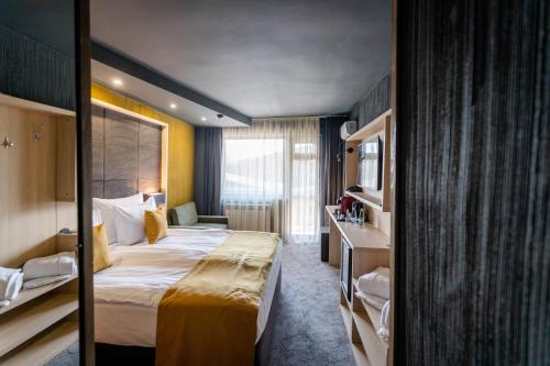 Cette chambre comprend un grand lit et une fenêtre. dans l'établissement Grande Vista Resort & Spa, à Tsigov Chark