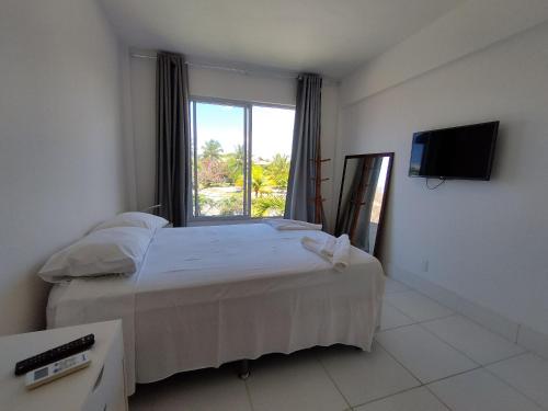 um quarto com uma cama e uma grande janela em Reserva Imbassaí Apartamento 1 quarto área de churrasco Bl2202 em Mata de São João