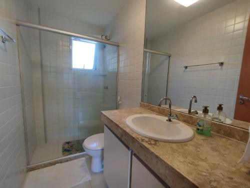 uma casa de banho com um lavatório, um chuveiro e um WC. em Reserva Imbassaí Apartamento 1 quarto área de churrasco Bl2202 em Mata de São João