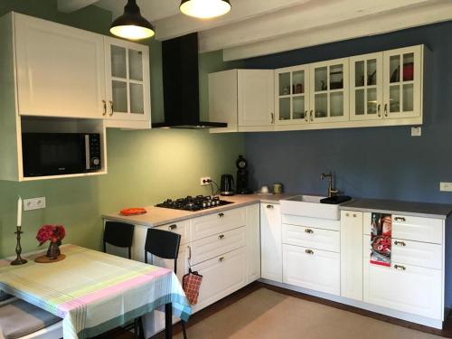 une cuisine avec des armoires blanches, une table et une cuisinière dans l'établissement The cosy retreat, à Mornay-sur-Allier