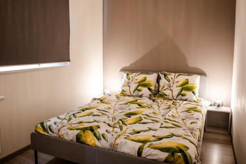a bed in a small room with a bedspread with leaves at Vakantiewoning op steenworp afstand van strand en havens in Yerseke